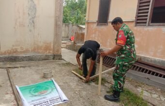 Dukung Transparansi Pembangunan Gampong, Babinsa Balohan Bantu Pasang Spanduk Informasi Proyek
