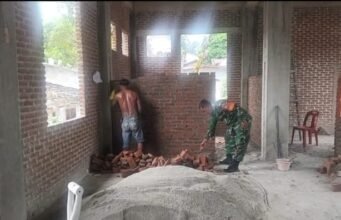 Wujudkan Kemanunggalan TNI-Rakyat, Babinsa Kuta Timu Bantu Pengerjaan Kantor Keuchik